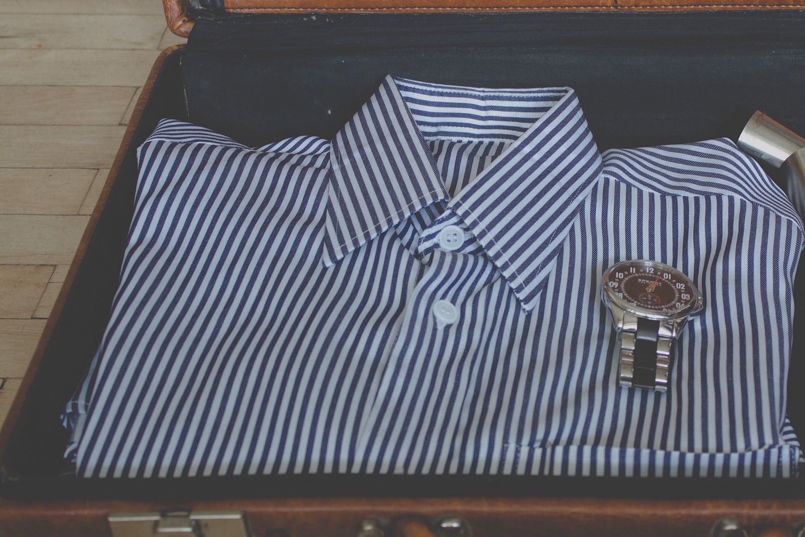 A carry-on suitcase being packed with a short stack of clothes